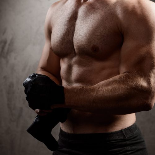 Close up photo of sportive man's body over dark background.